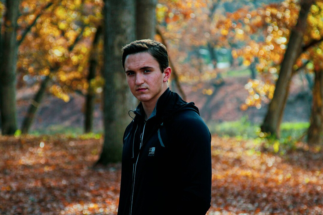 Portrait of a man in his thirties with short brown hair in a dark sweater