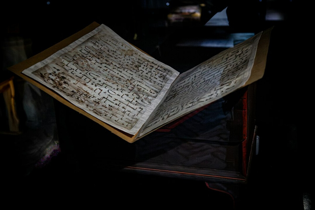 Middle-aged woman archivist in cotton gloves examining an old document at a desk